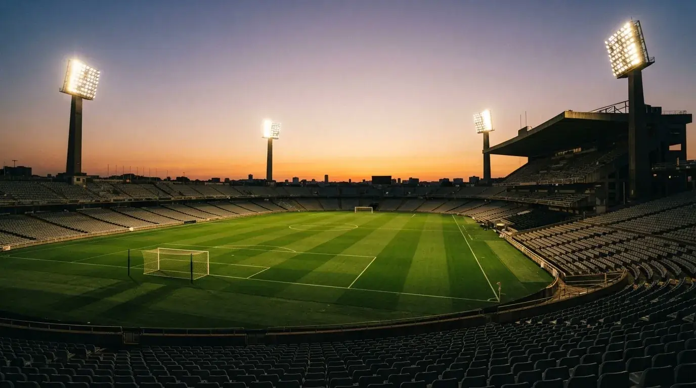 Un estadio de fútbol vacío con torres de iluminación al atardecer