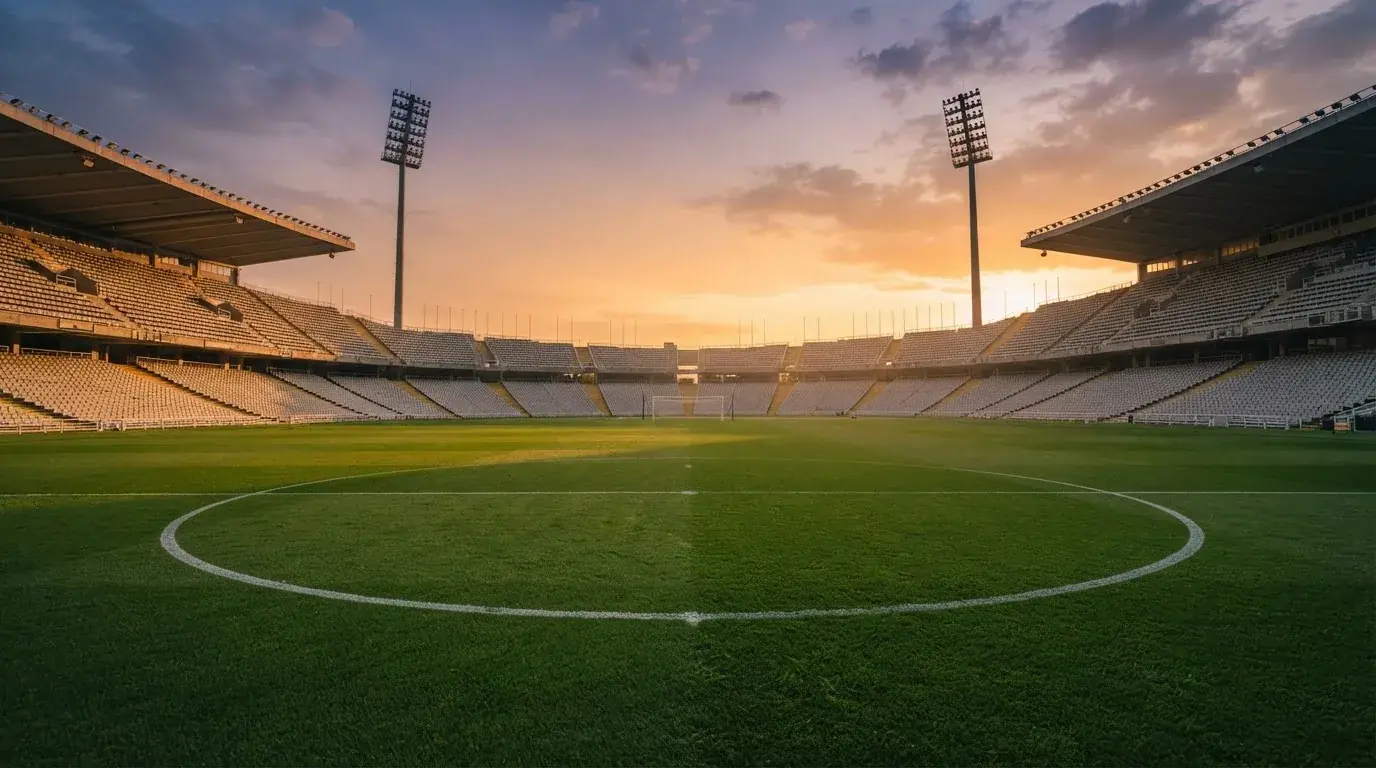 Un estadio de fútbol vacío con torres de iluminación al atardecer