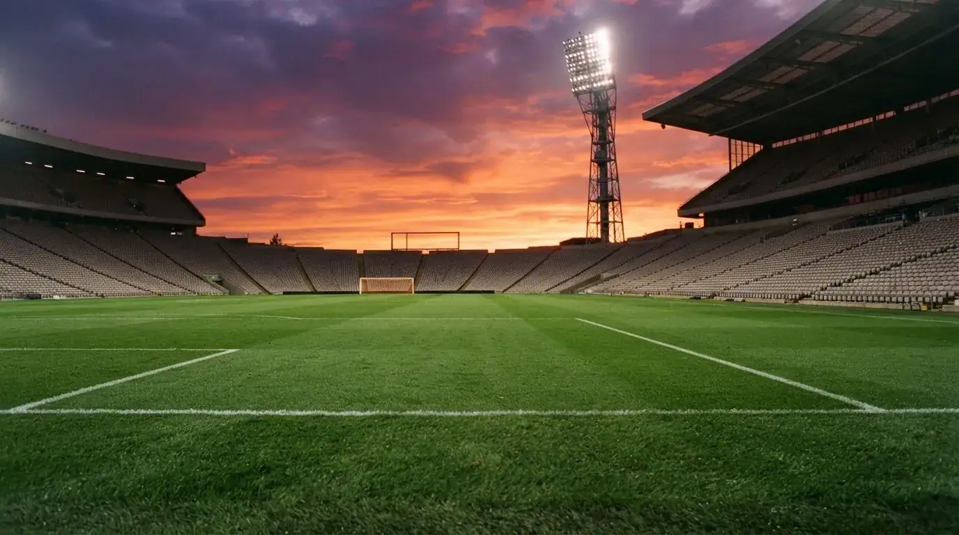 Un estadio de fútbol vacío con torres de iluminación al atardecer
