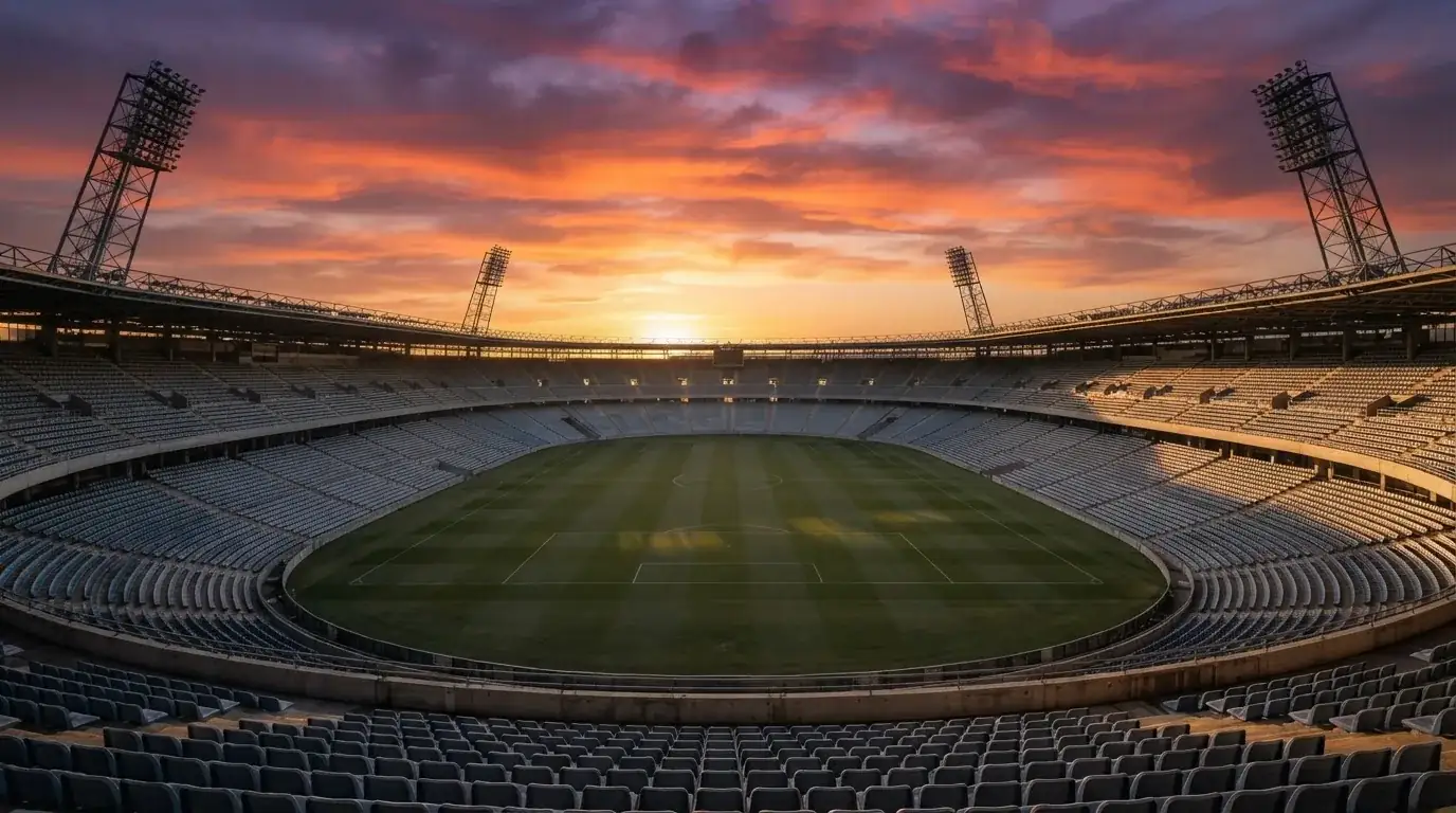 Un estadio de fútbol vacío con torres de iluminación al atardecer