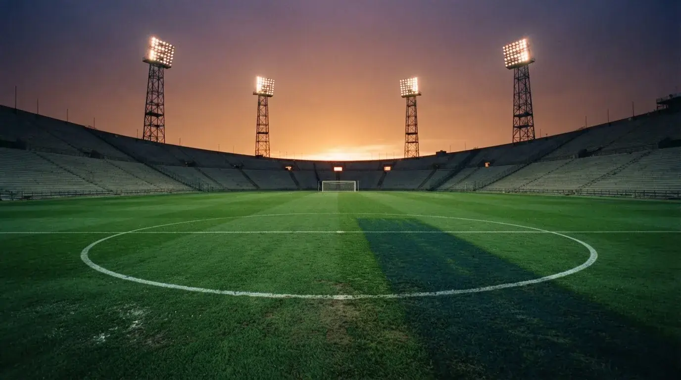 Un estadio de fútbol vacío con torres de iluminación al atardecer