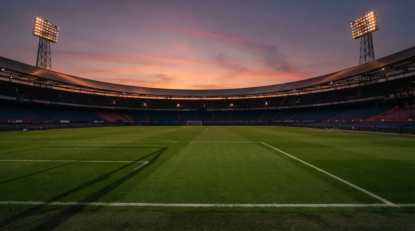 Un estadio de fútbol vacío con torres de iluminación al atardecer