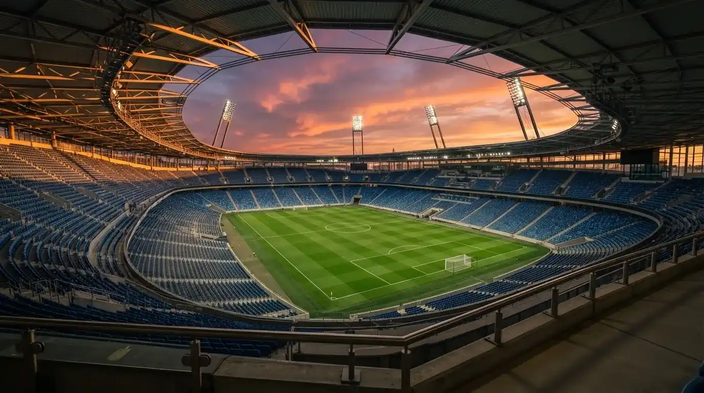 Un estadio de fútbol vacío con torres de iluminación al atardecer