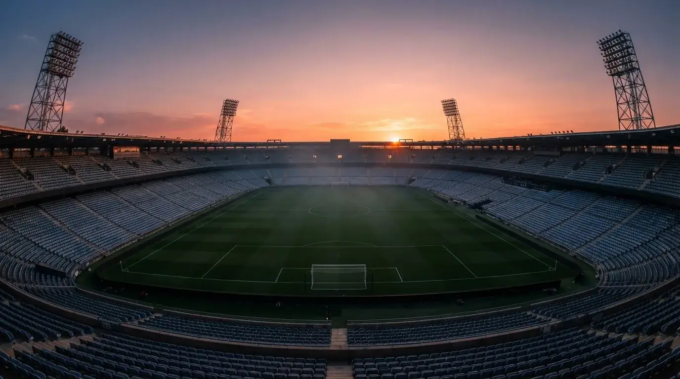 Un estadio de fútbol vacío con torres de iluminación al atardecer