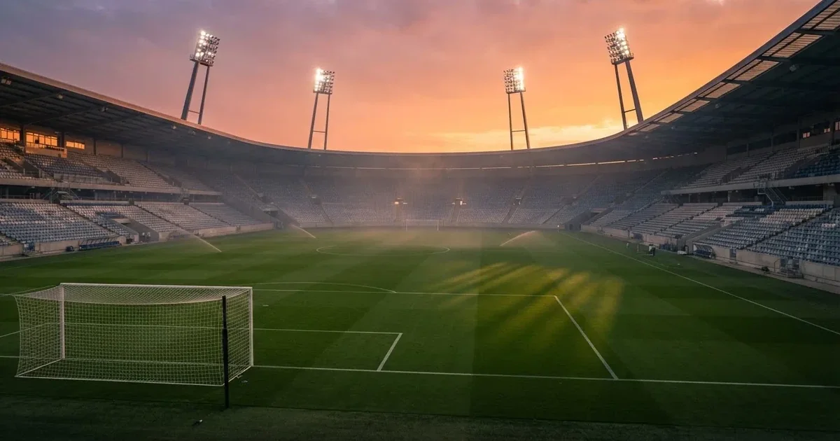 Un estadio de fútbol vacío con torres de iluminación al atardecer