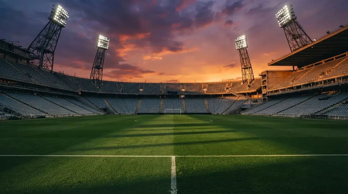 Un estadio de fútbol vacío con torres de iluminación al atardecer