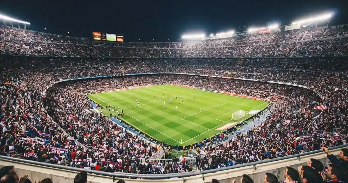 Un pabellón deportivo lleno bajo los focos, fotografiado desde muy lejos