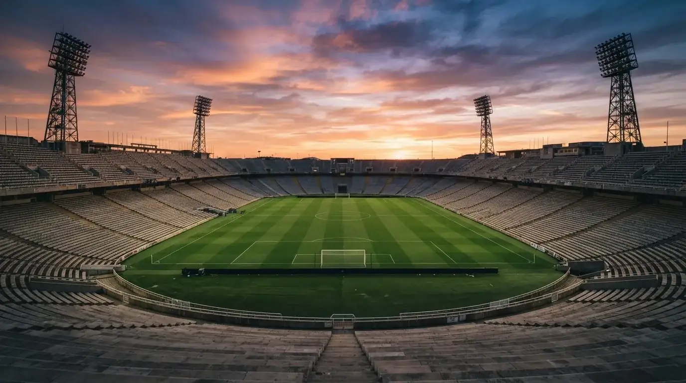 Un estadio de fútbol vacío con torres de iluminación al atardecer