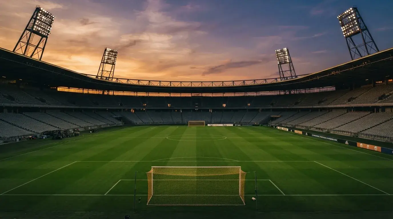 Un estadio de fútbol vacío con torres de iluminación al atardecer
