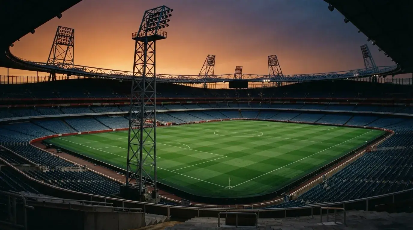 Un estadio de fútbol vacío con torres de iluminación al atardecer