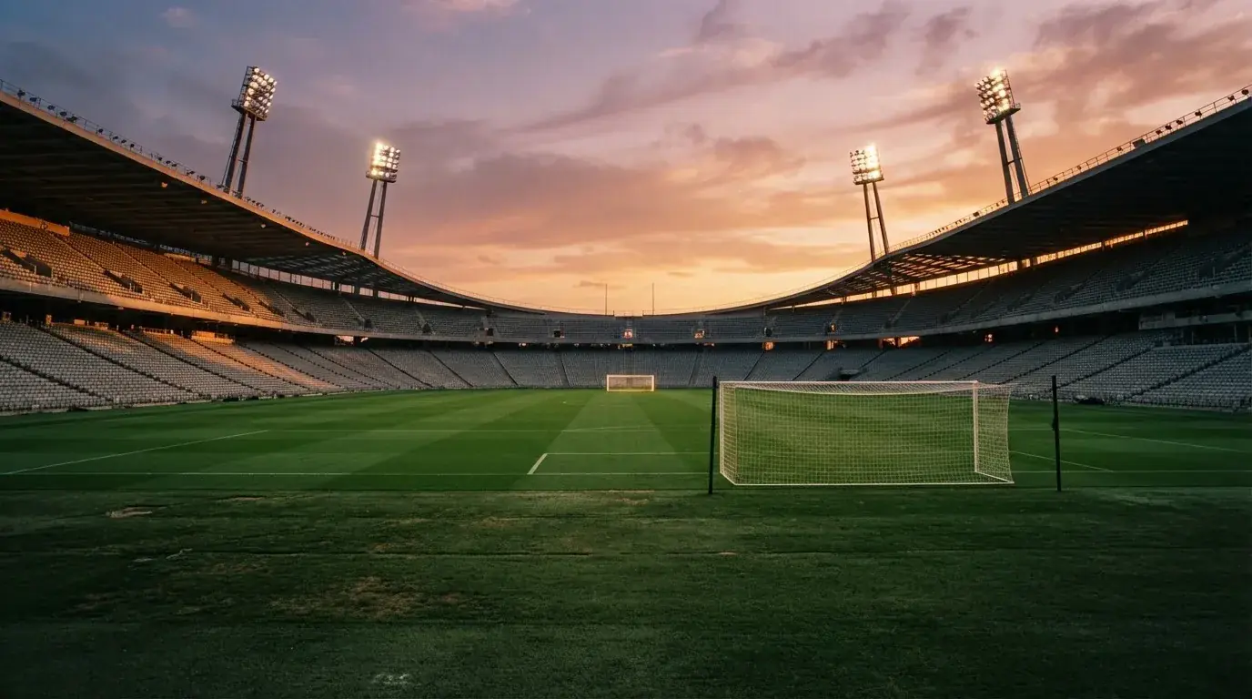 Un estadio de fútbol vacío con torres de iluminación al atardecer