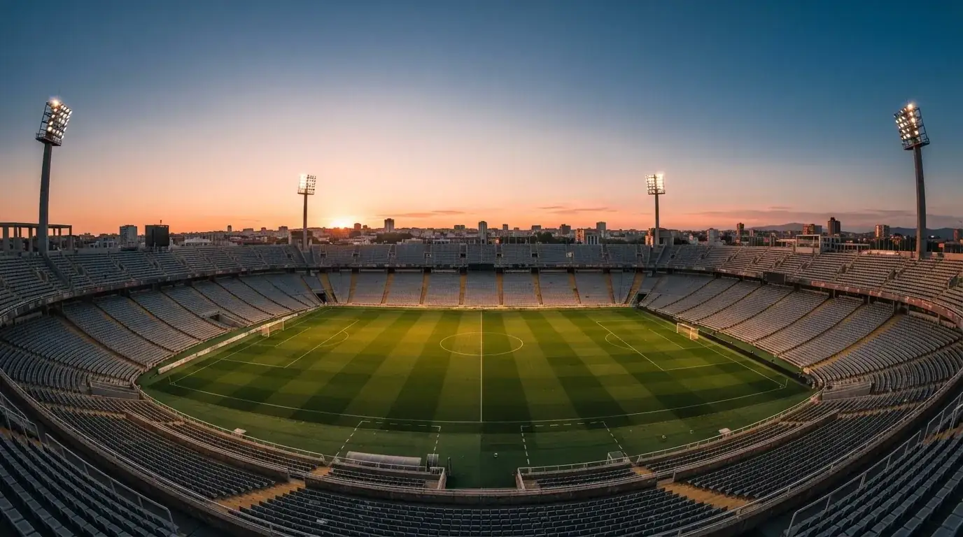 Un estadio de fútbol vacío con torres de iluminación al atardecer
