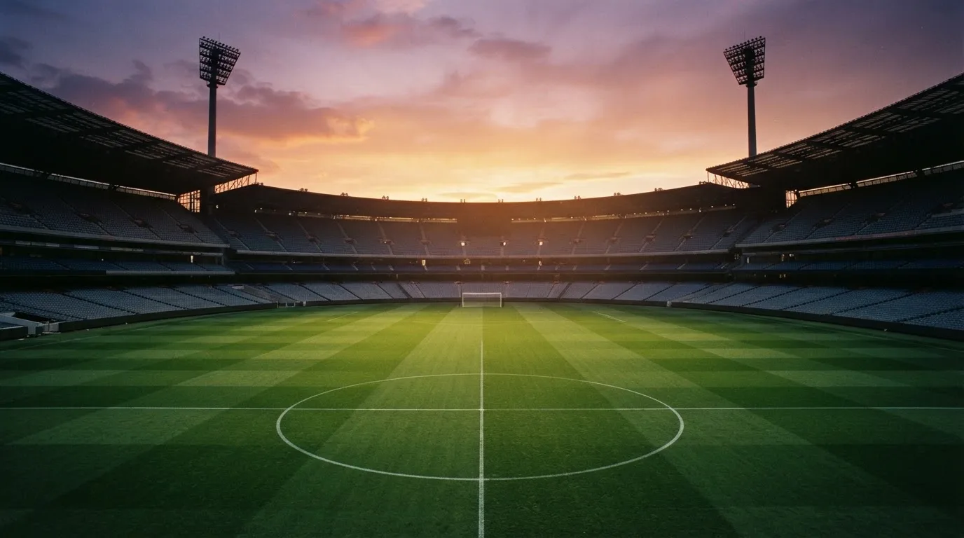 Un estadio de fútbol vacío con torres de iluminación al atardecer