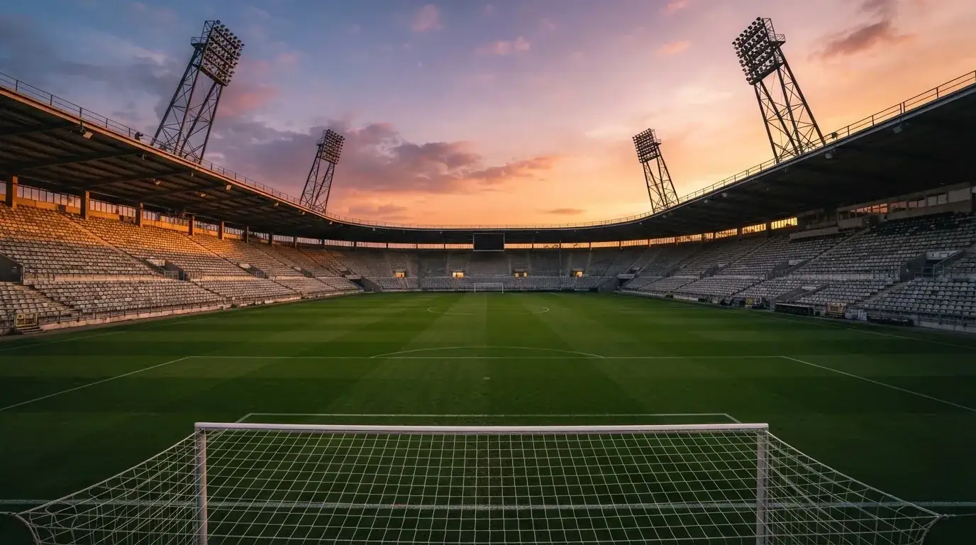 Un estadio de fútbol vacío con torres de iluminación al atardecer
