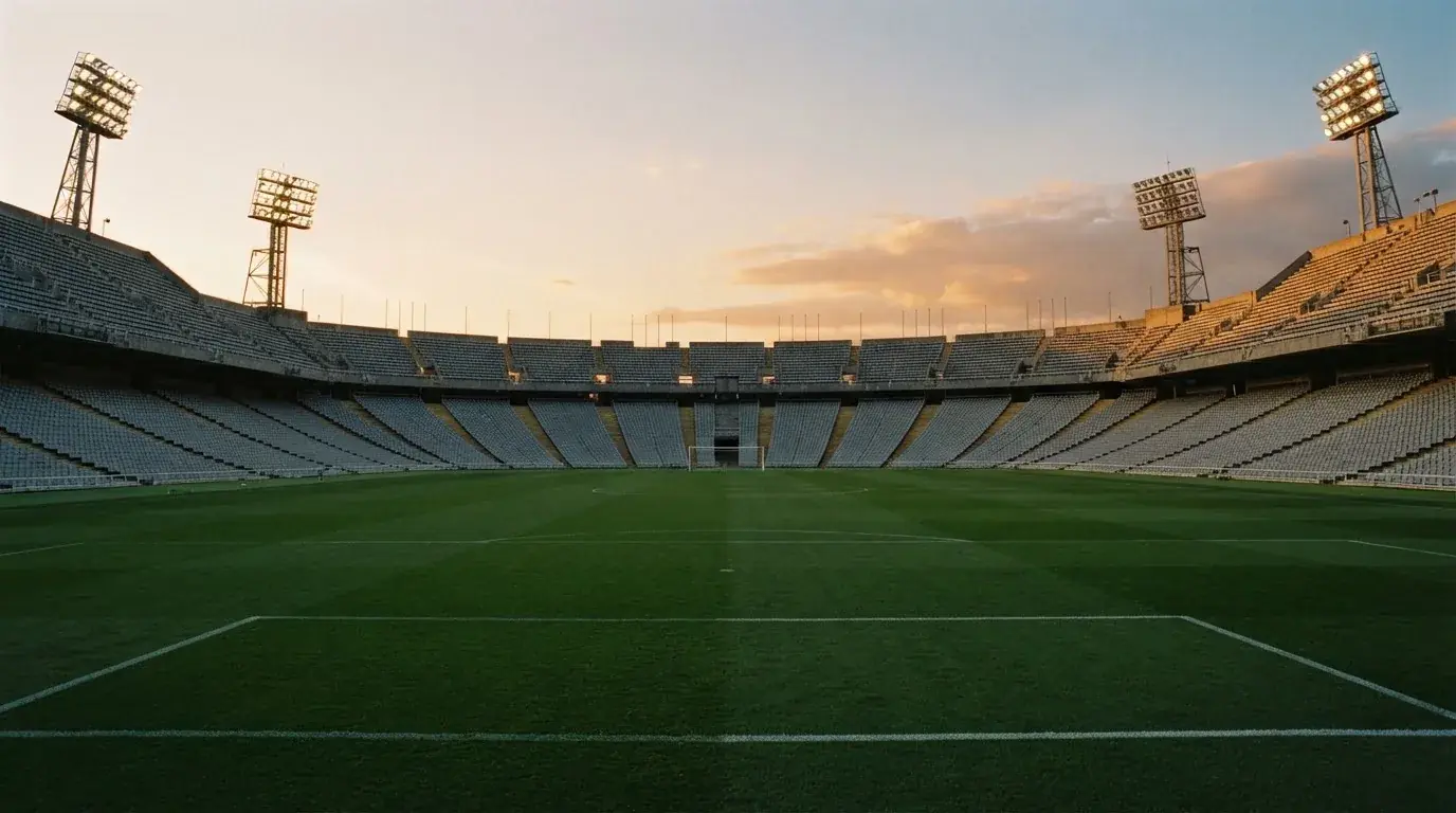 Un estadio de fútbol vacío con torres de iluminación al atardecer