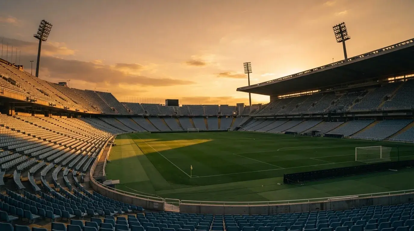 Un estadio de fútbol vacío con torres de iluminación al atardecer